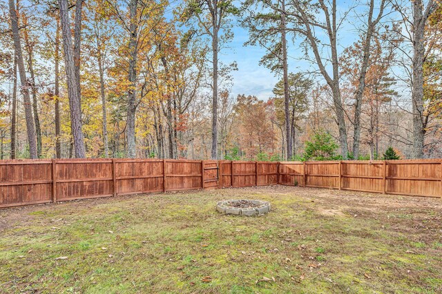 view of yard featuring a fenced backyard and a fire pit