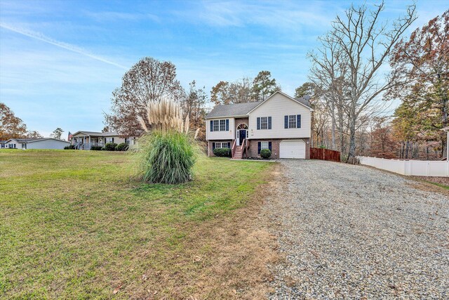split foyer home featuring a garage, gravel driveway, fence, a front lawn, and stairs