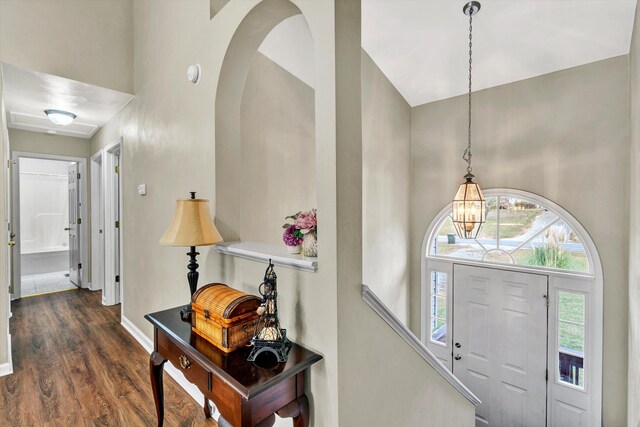 foyer entrance featuring baseboards, wood finished floors, a notable chandelier, and high vaulted ceiling