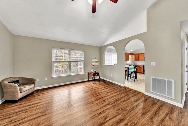 unfurnished room with light wood-style floors, arched walkways, a ceiling fan, baseboards, and visible vents