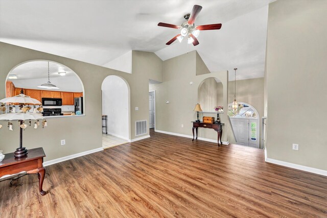 living area featuring a ceiling fan, visible vents, arched walkways, high vaulted ceiling, and light wood-style floors