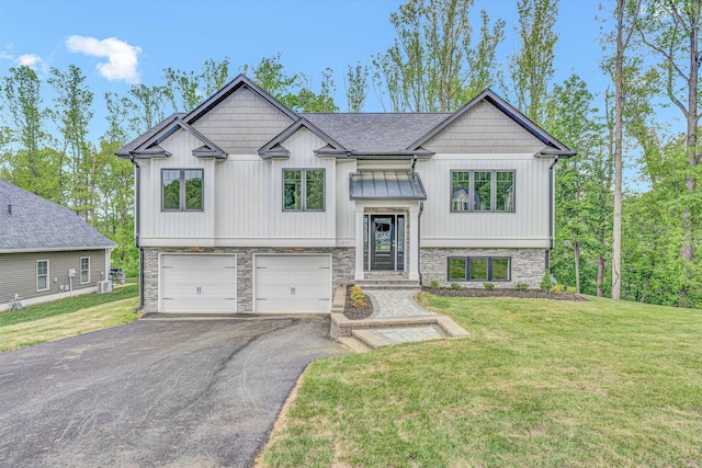 bi-level home with a standing seam roof, a front yard, aphalt driveway, an attached garage, and stone siding
