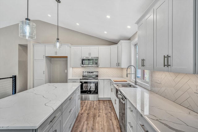 kitchen featuring lofted ceiling, light wood-style floors, a sink, appliances with stainless steel finishes, and backsplash