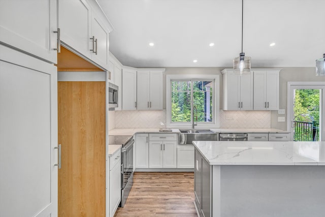 kitchen featuring backsplash, a sink, light stone counters, stainless steel appliances, and recessed lighting