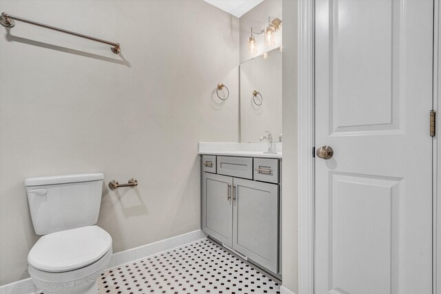 half bathroom featuring toilet, baseboards, tile patterned floors, and vanity