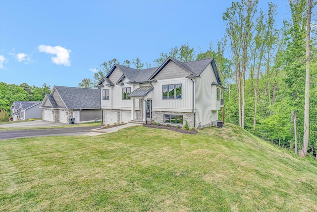 raised ranch with board and batten siding, a front yard, and a garage