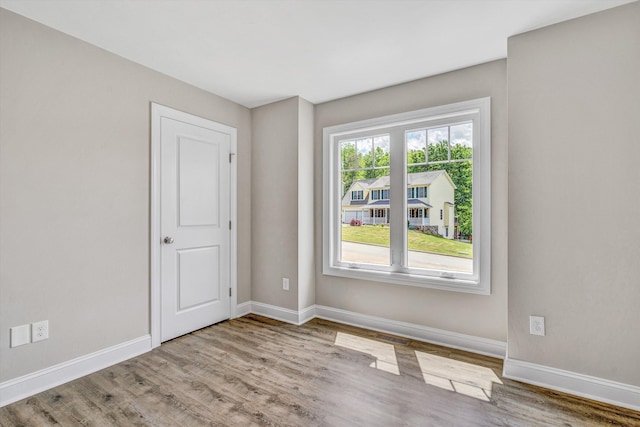 spare room with baseboards and wood finished floors