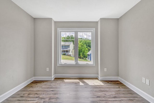 spare room featuring baseboards and wood finished floors