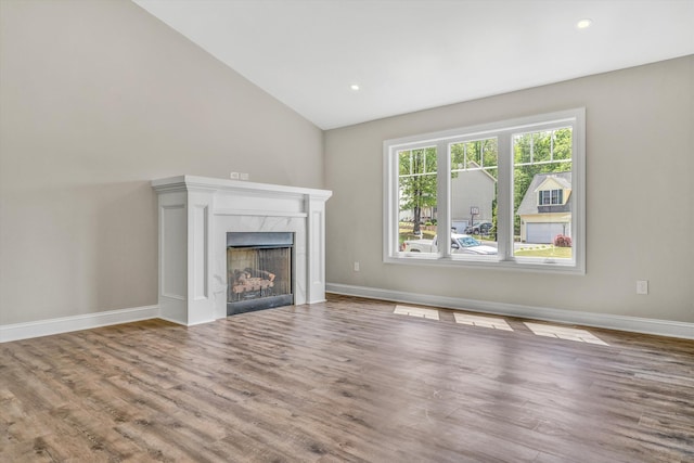 unfurnished living room with a high end fireplace, wood finished floors, baseboards, lofted ceiling, and recessed lighting