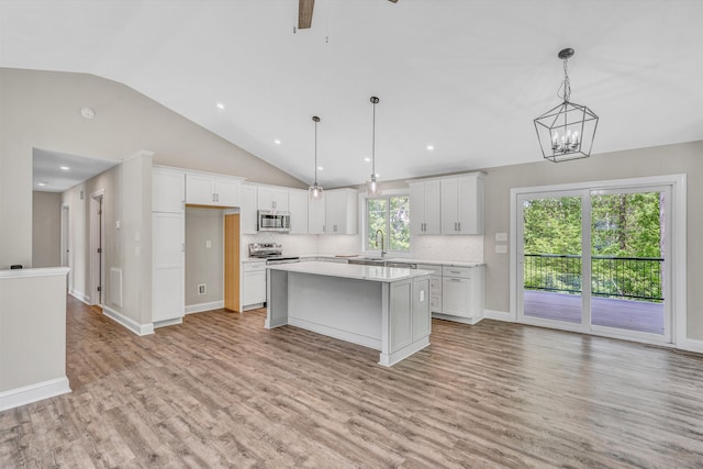 kitchen featuring a kitchen island, vaulted ceiling, light wood-type flooring, light countertops, and stainless steel appliances