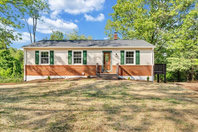 view of front of house with brick siding, a chimney, and a front lawn