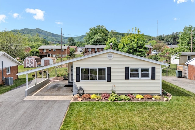 view of front of property featuring driveway, central AC, an outdoor structure, a mountain view, and a shed