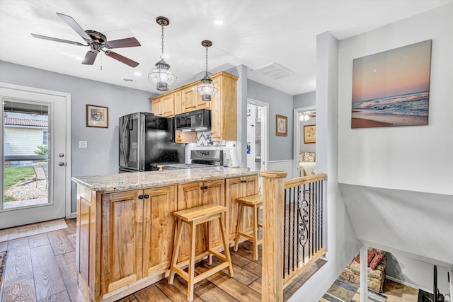 kitchen with light stone counters, light wood-style flooring, a peninsula, and black appliances