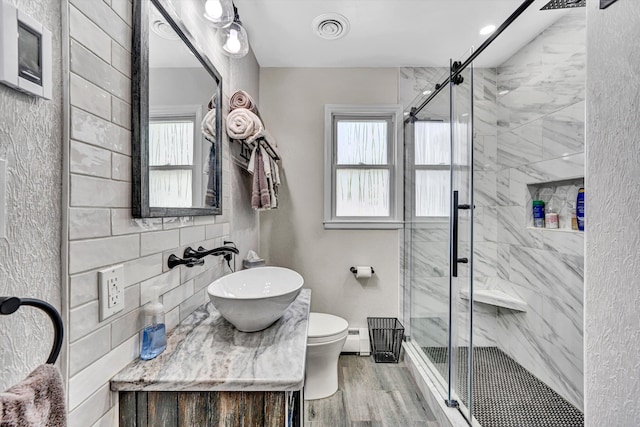 bathroom with visible vents, a stall shower, wood finished floors, vanity, and toilet