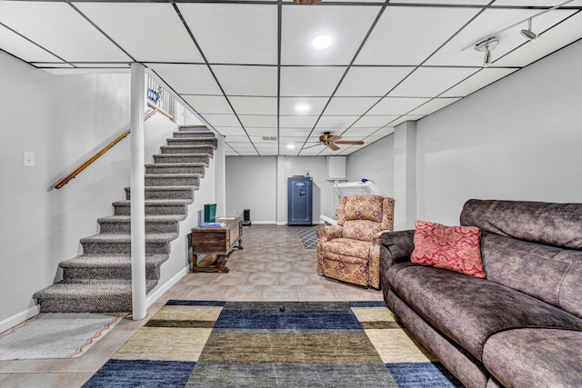 living area featuring ceiling fan, stairway, baseboards, a drop ceiling, and recessed lighting