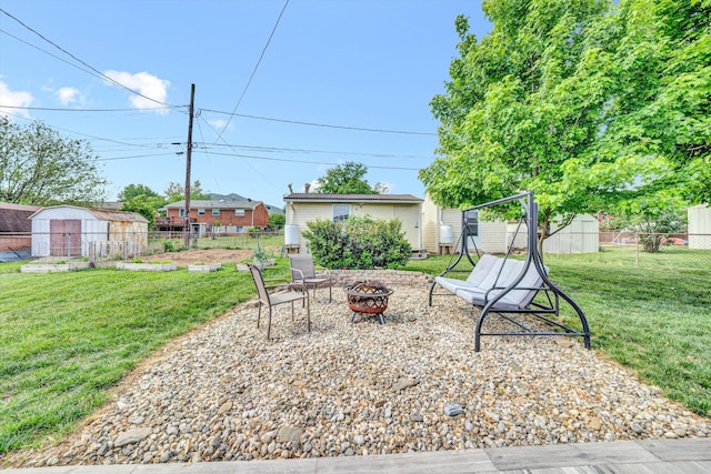 view of patio featuring an outdoor structure, fence, a shed, and an outdoor fire pit