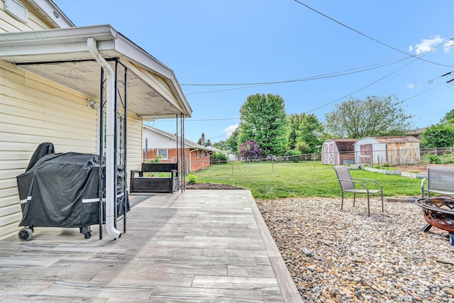 view of patio with fence, an outbuilding, an outdoor fire pit, and a shed