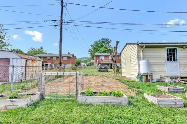 view of yard featuring fence, an outdoor structure, and a vegetable garden