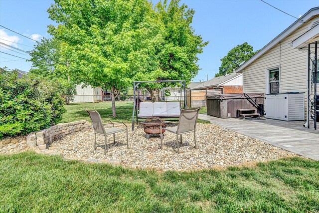 view of patio with a fenced backyard, a hot tub, and an outdoor fire pit
