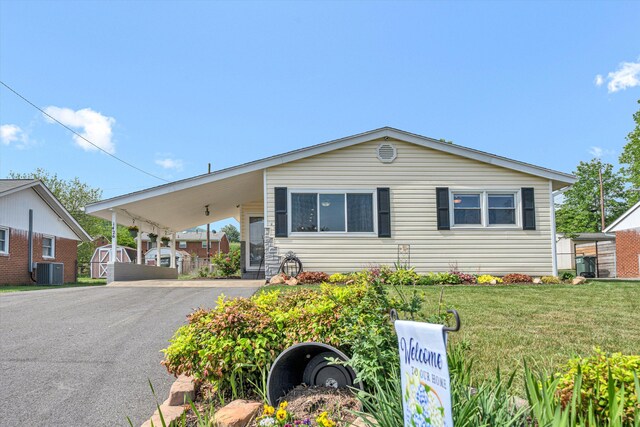 manufactured / mobile home with a storage unit, a front lawn, aphalt driveway, an attached carport, and central AC unit