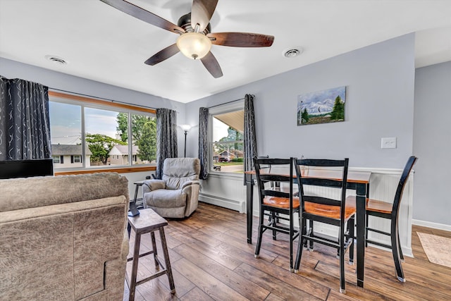 dining room featuring visible vents, wood-type flooring, ceiling fan, and baseboard heating