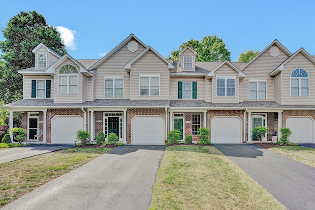 multi unit property featuring brick siding, an attached garage, and driveway