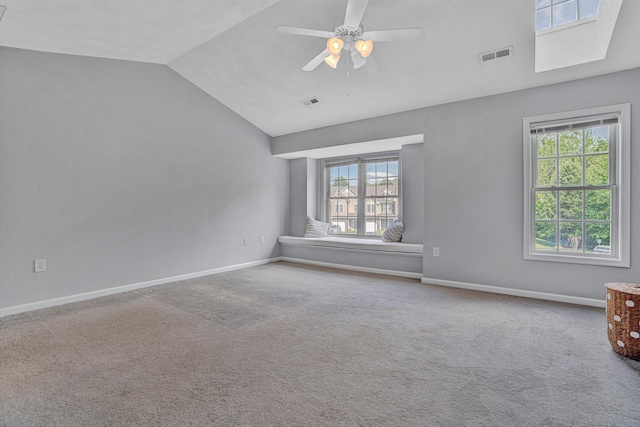 carpeted empty room with visible vents, baseboards, lofted ceiling, and a healthy amount of sunlight