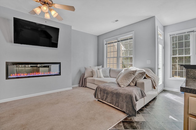 living room with a glass covered fireplace, visible vents, and a wealth of natural light