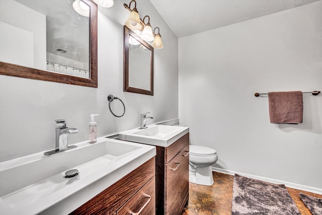 full bathroom featuring toilet, baseboards, two vanities, and a sink