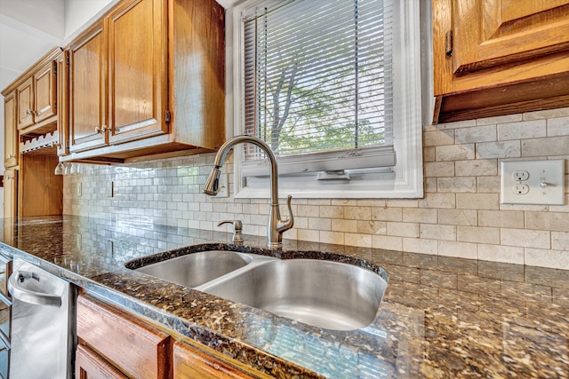 kitchen featuring a sink, dark stone countertops, backsplash, and brown cabinets