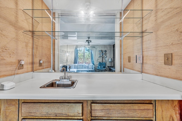 kitchen with ceiling fan, brown cabinetry, and a sink