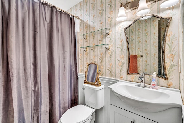 full bath featuring vanity, a wainscoted wall, toilet, a decorative wall, and wallpapered walls