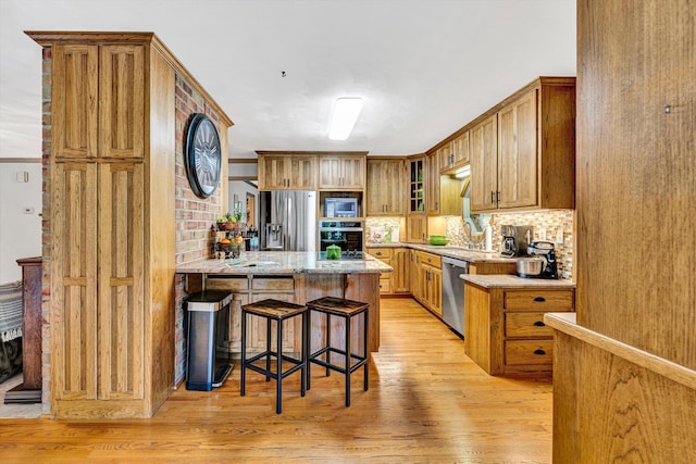 5531 Bethlehem Rd, Boones Mill, VA 24065 - kitchen with stainless steel appliances, light wood-style floors, a breakfast bar, glass insert cabinets, and a peninsula