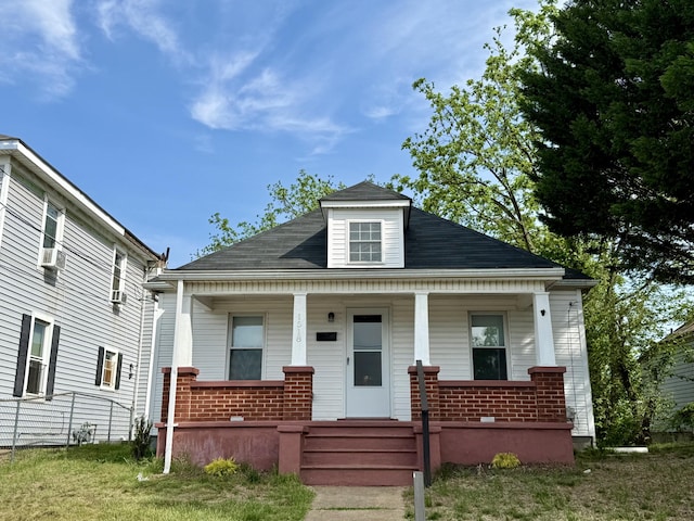 view of front facade featuring a porch, brick siding, and cooling unit
