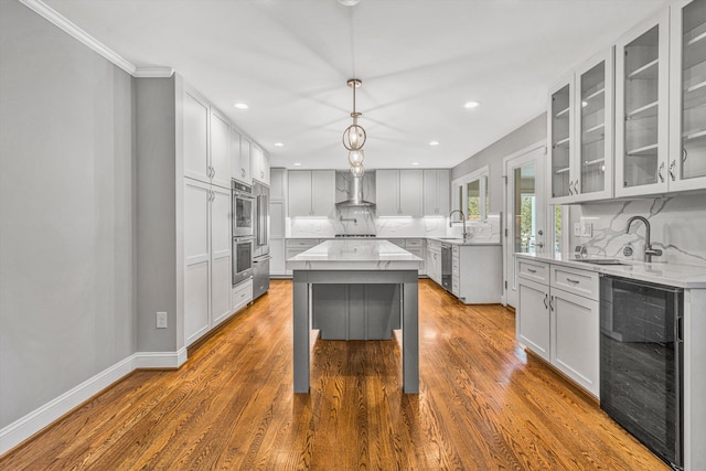 kitchen with wine cooler, a sink, tasteful backsplash, wall chimney exhaust hood, and recessed lighting