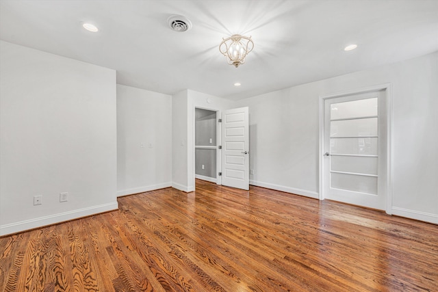 unfurnished bedroom with wood finished floors, baseboards, recessed lighting, and a chandelier