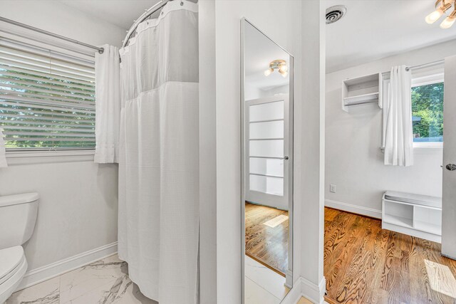 full bath featuring toilet, healthy amount of natural light, and baseboards