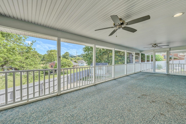 unfurnished sunroom with a ceiling fan and plenty of natural light