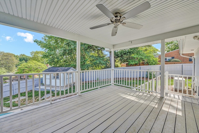 deck featuring an outdoor structure, a shed, a fenced backyard, and a ceiling fan