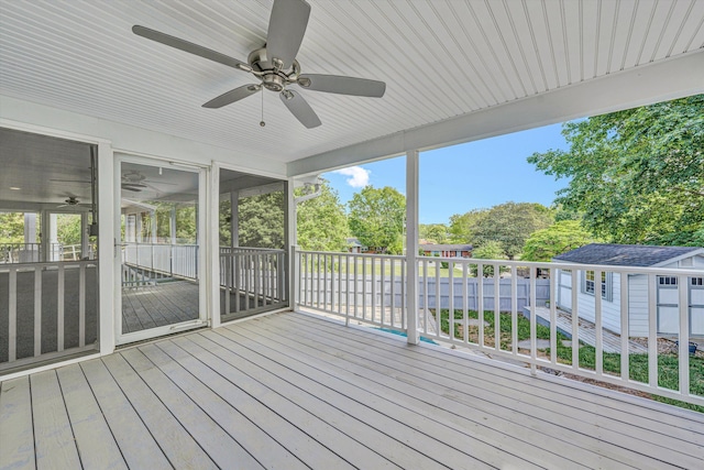 deck with ceiling fan, a storage unit, an outdoor structure, and view of scattered trees