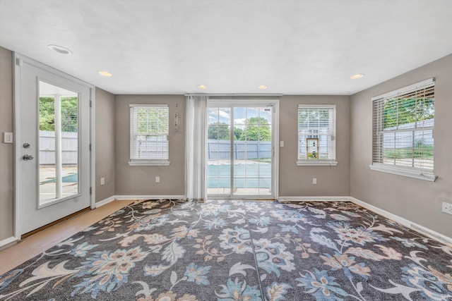 entryway with healthy amount of natural light, baseboards, carpet floors, and recessed lighting