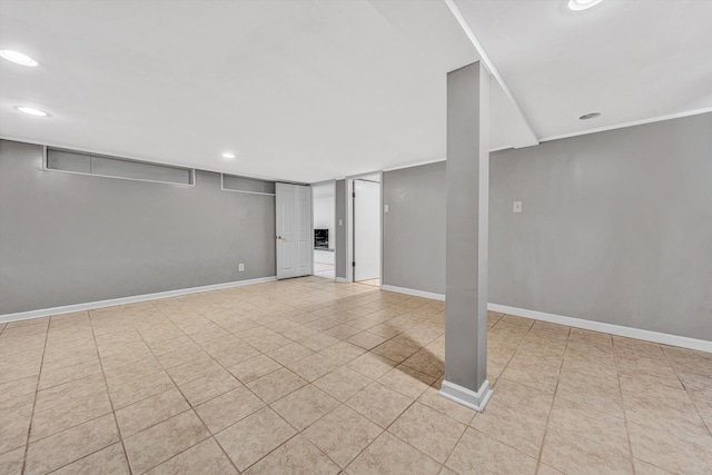 finished below grade area featuring light tile patterned flooring, recessed lighting, and baseboards