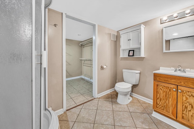 bathroom with tile patterned floors, baseboards, vanity, toilet, and a shower with shower door