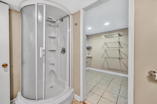 bathroom with a stall shower, tile patterned floors, and baseboards