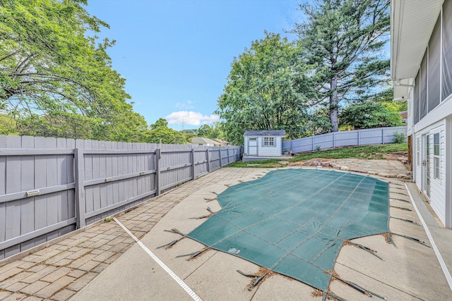 view of swimming pool featuring a patio area, a fenced backyard, a storage shed, and an outdoor structure