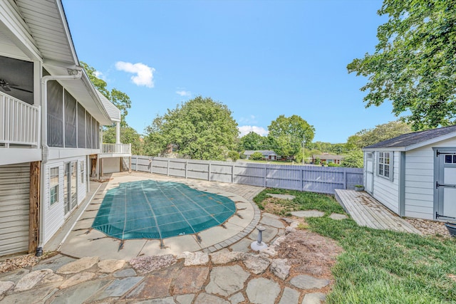 view of swimming pool featuring a fenced backyard, a storage unit, a sunroom, an outbuilding, and a patio area