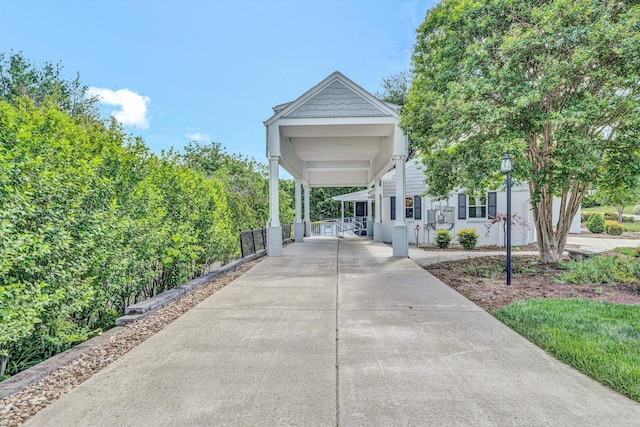 view of side of home with concrete driveway, fence, and a carport