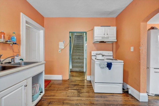 kitchen with dark wood-style flooring, arched walkways, under cabinet range hood, white appliances, and white cabinetry