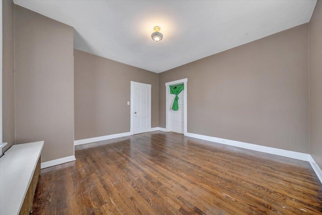 spare room with baseboards and wood finished floors