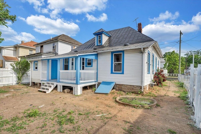 rear view of house featuring fence, a wooden deck, and a chimney
